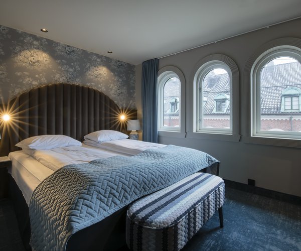 Standard room with double bed beside arched windows