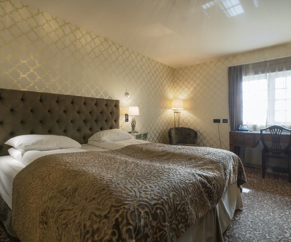 Double bed with patterned wallpaper in the deluxe room