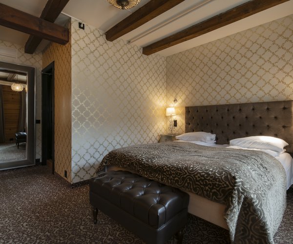 Double bed beneath exposed beams in the deluxe room