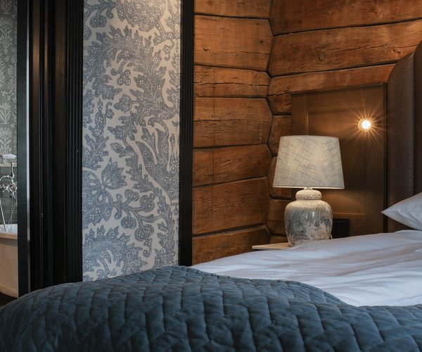 Bed against the wood-panelled wall in the deluxe room