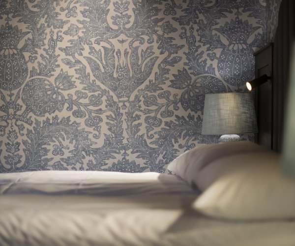Double bed with patterned wallpaper in the deluxe room