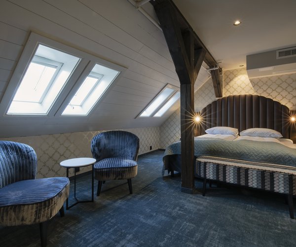 Armchairs beside the bed beneath the skylight