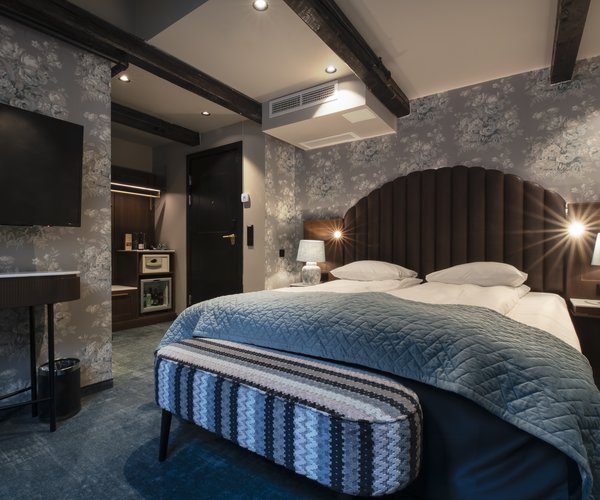 Deluxe room with sloped ceiling and double bed beneath the beams
