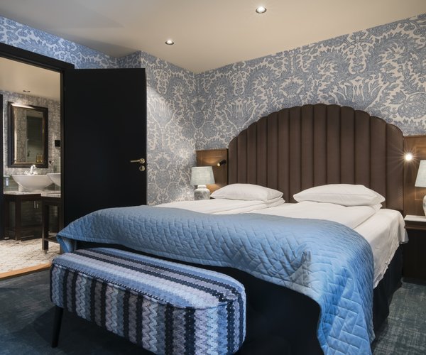 Junior suite bedroom with blue upholstered headboard