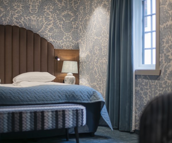 Double bed with blue textiles beside the window