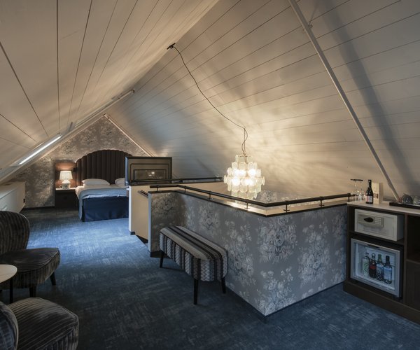 Junior suite with bed and seating area under the sloping ceiling