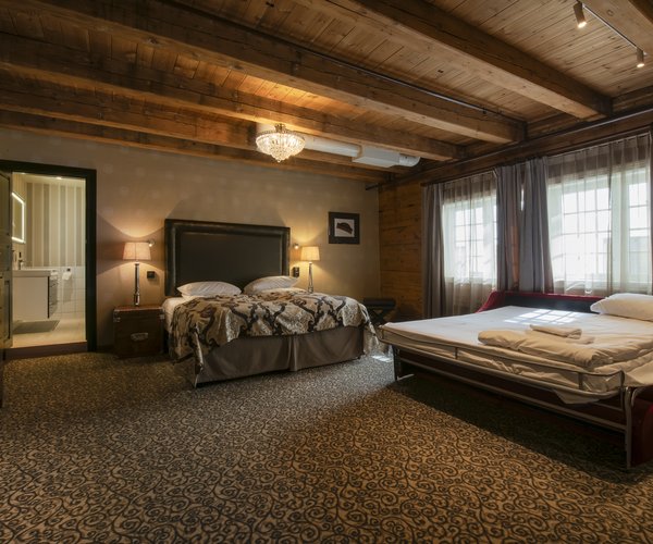 Suite bedroom with wood-panelled walls and beamed ceiling