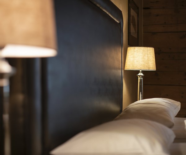 Bedside lamp and pillows in the warmly lit suite