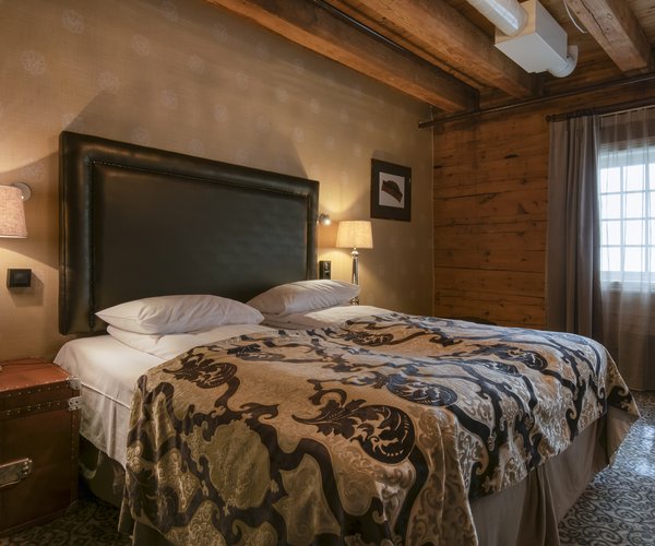 Double bed with patterned throw against panelled wooden walls