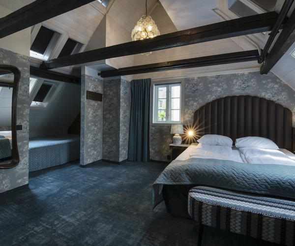 Double bed with arched headboard beneath the suite's sloping beamed ceiling