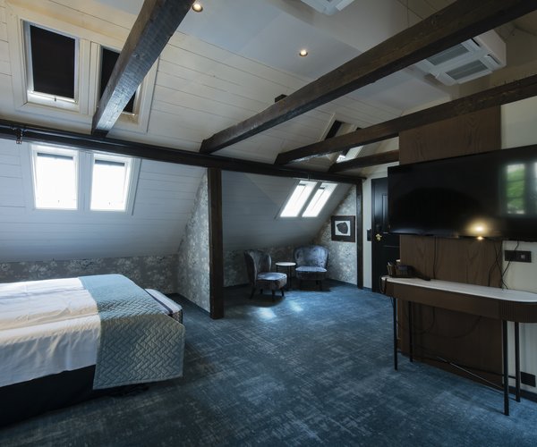 Bed, desk and wall-mounted television in the suite